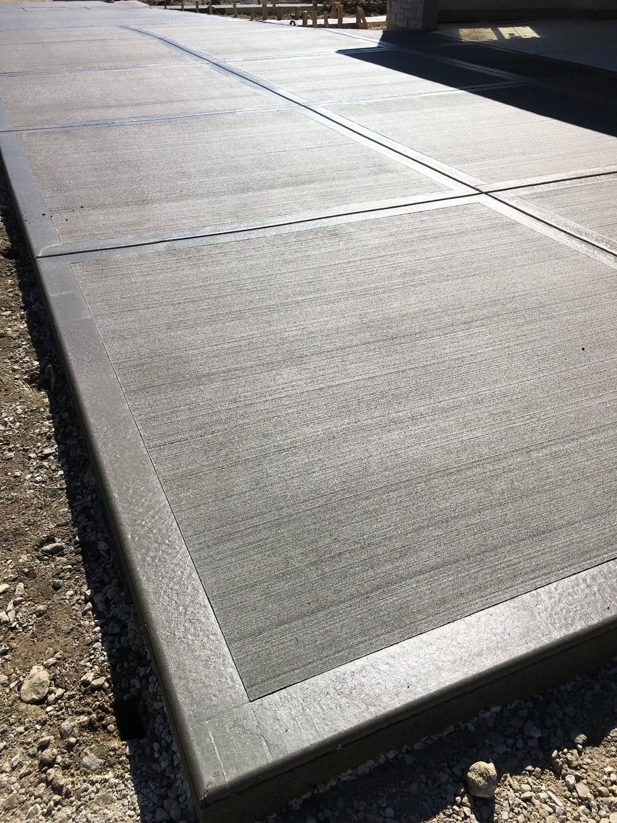 Close view of broom-finished concrete sidewalk slab with clean edge lines