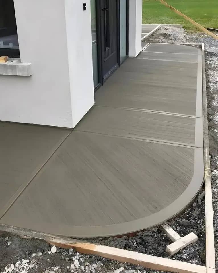 Curved broom-finished concrete walkway beside a home exterior