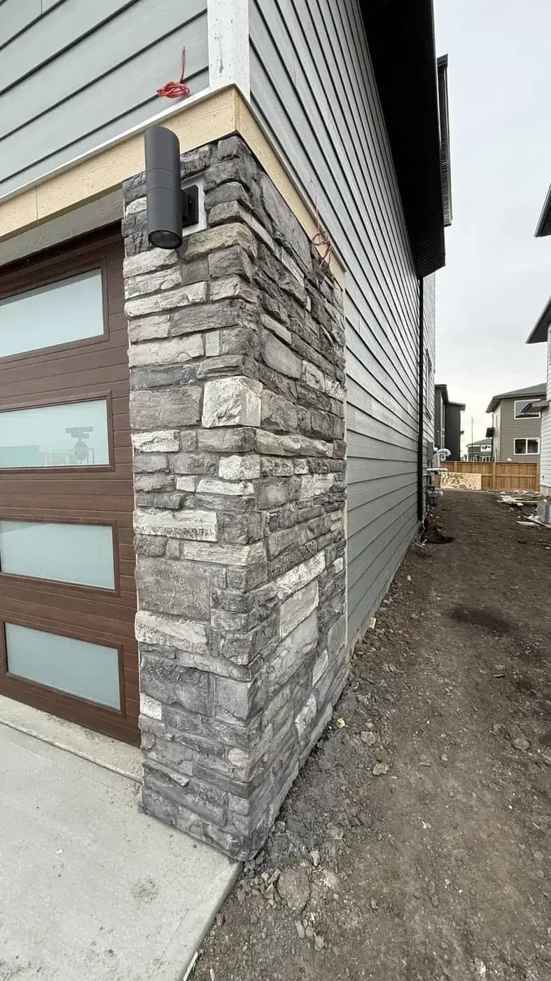 Narrow garage-side stone column beside siding and concrete surface